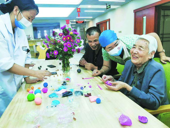 社区养老服务中心内，老人们和护理人员一起做手工。何敏 摄