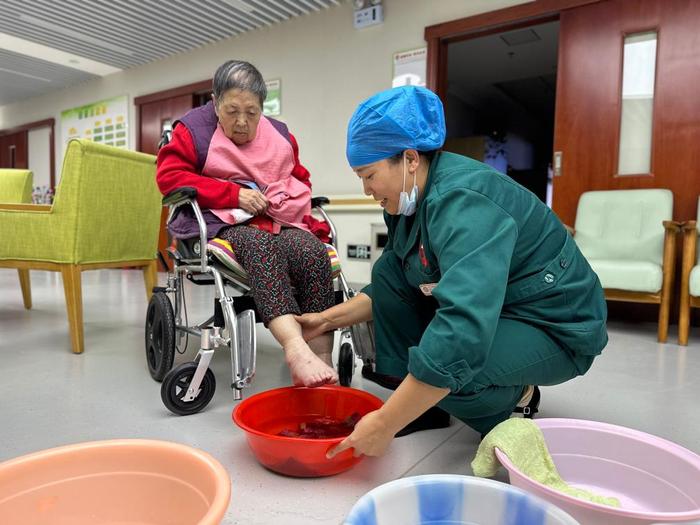 2023年10月17日，在青海省西宁市城西区通海路街道综合养老服务中心，养老护理员为入住的老人洗脚。新华社记者张子琪摄