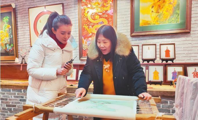         满绣非遗传承人王立君（右）在展示满绣作品。本报记者   徐   鑫   摄