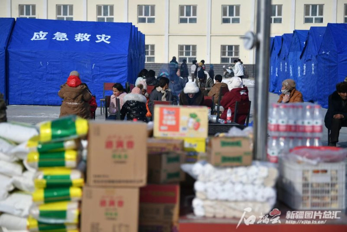1月23日，乌什县亚曼苏柯尔克孜族乡喀拉苏村村民在村委会的篮球场上烤火，一旁是各类援助物资。