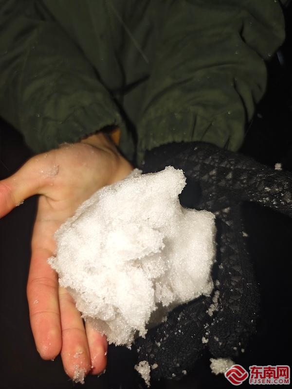 22日夜间，在鼓岭景区，游客捧起一把飘落的雪花。东南网记者 洪振威 摄