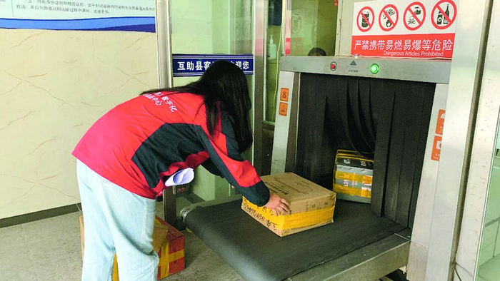 互助土族自治县客运站工作人员李燕宁将发往各村的快递逐一放在安检传送带上。倪晓颖 摄