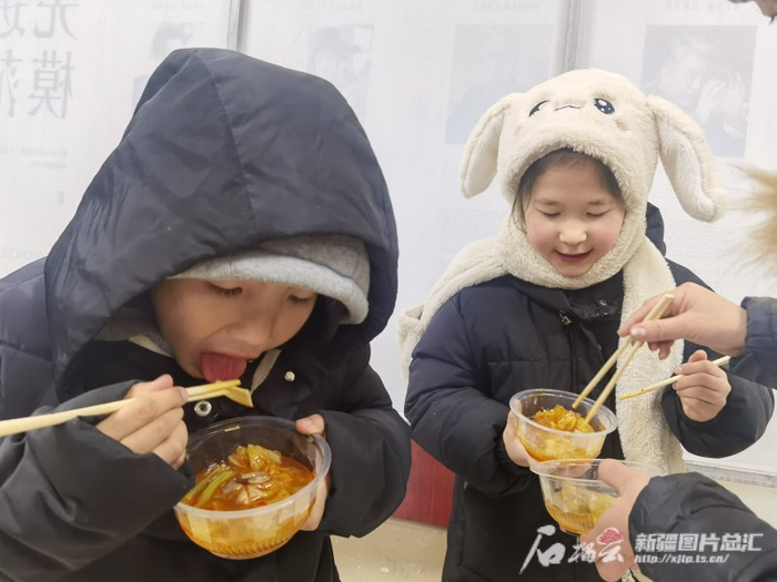 阿合奇县科技文化体育中心安置点里，孩子们正在吃晚饭。石榴云/新疆日报 记者 刘萌萌摄