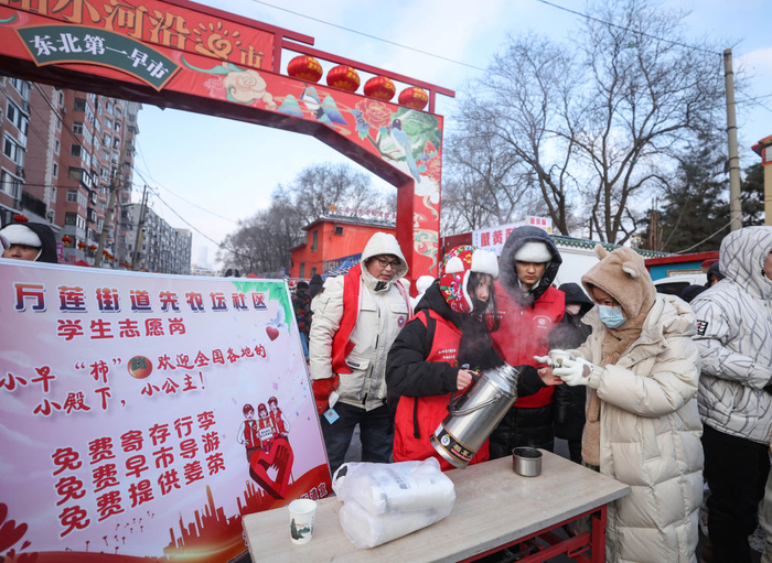 2024年1月21日，在辽宁沈阳小河沿早市，志愿者为游客提供免费热水。新华社记者 龙雷 摄