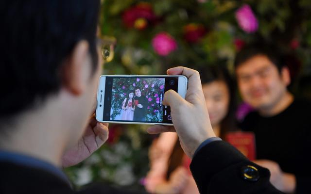 ▲资料图：在辽宁沈阳市皇姑区民政局婚姻登记处，两位新人手持结婚证拍照留念。图/新华社