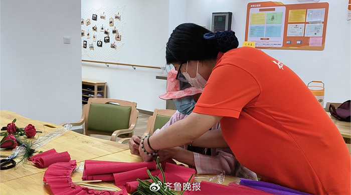 一位老人在济南一家养老机构员工的陪伴下制作手工。实习生 史继超 摄