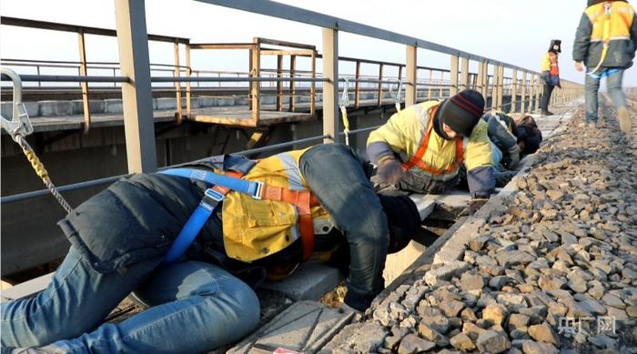 桥隧工躺在水泥板上进行塔架加固作业