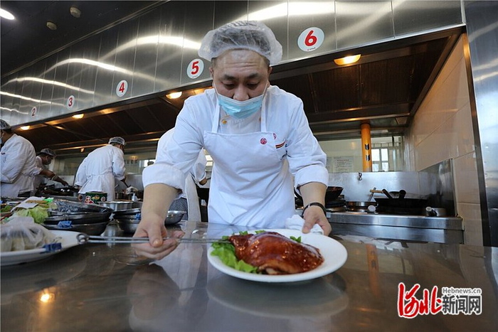 1月24日中午，在唐山鸿宴饭庄后厨，厨师把做好的“崇礼菜单”菜品“鸿宴肘子”进行摆盘。 河北日报记者 王育民摄