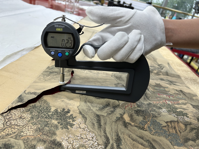 　　修复前，对《赵垓山水图轴》测试厚度。（受访者供图）