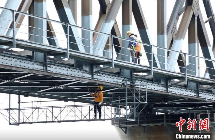 1月25日，衡阳工务段桥隧工在“移动吊篮”上检查洣河铁桥底部钢梁。刘欢摄
