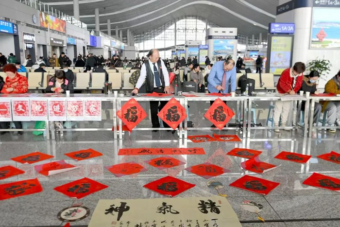 　　1月26日，山东省青岛西站，文化志愿者在给旅客书写福字和剪纸。工人日报通讯员 俞方平 摄