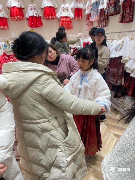 林女士的女儿试穿拜年服。记者 滕一韬 摄