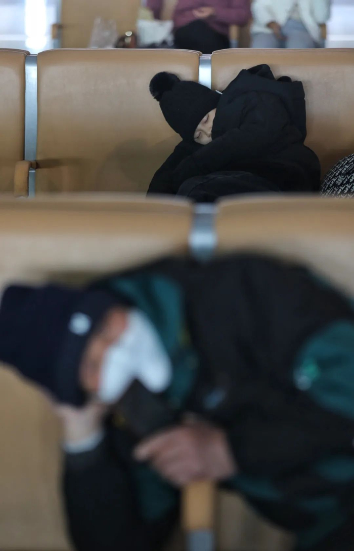 　　1月26日，2024年春运首日，北京丰台站，候车的旅客在座椅上休息。工人日报记者 杨登峰 摄