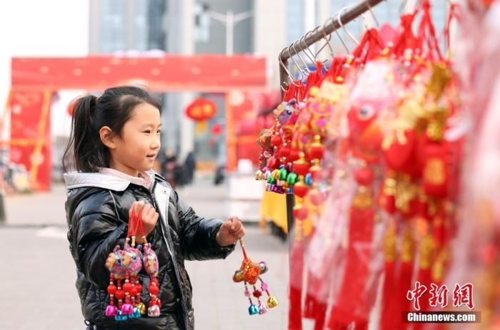 图为小朋友选购“龙年”装饰品。中新社记者 张宇 摄