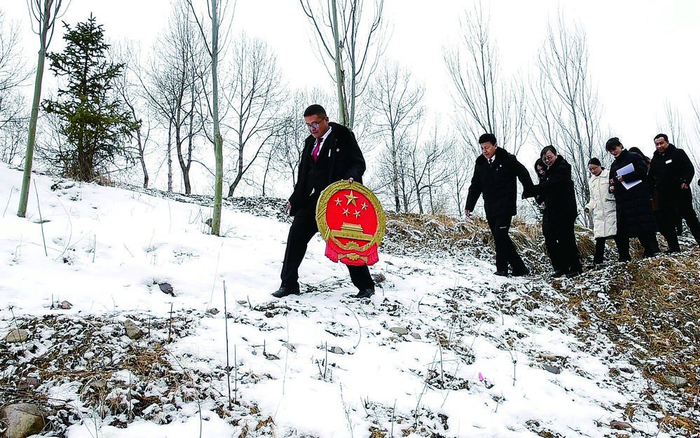 互助土族自治县人民法院家事审判团队法官迎着漫天的飞雪，手捧国徽，入村开展巡回审判。省高级人民法院供图