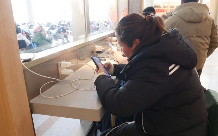 旅客坐在自助服务区内为手机充电。新京报记者 王贵彬 摄