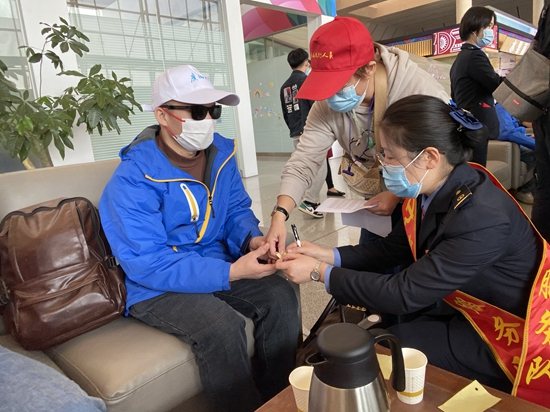 秦蓉蓉将印有旅途注意事项的盲文纸条交给视障旅客，方便他们乘车。通讯员 于莉/摄