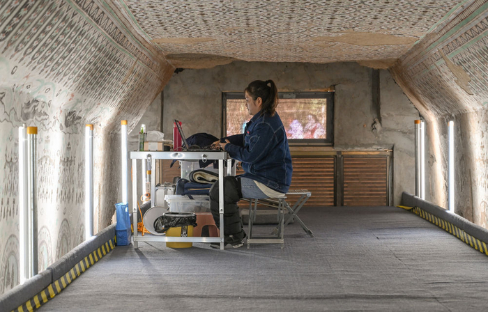 在敦煌莫高窟正在保护修缮的第55窟内，一位文保工作者对采集的数据进行整理（2023年8月3日摄）。新华社记者 李贺 摄