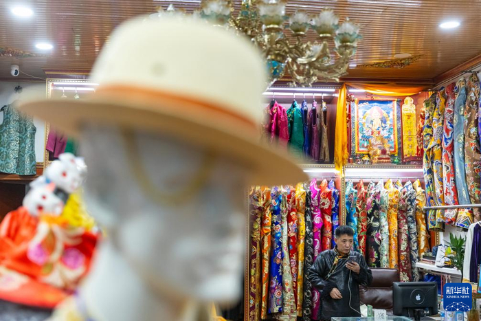 尼玛王登在店里通过手机与客户联系，了解客户定制藏装的需求（1月4日摄）。新华社记者沈伯韩摄