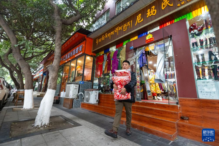 尼玛王登抱着新做好的藏装准备交给快递员发走（1月4日摄）。新华社记者沈伯韩摄