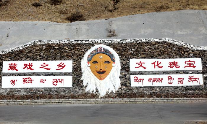 扎西曲登社区入口的雅砻扎西雪巴藏戏面具和标语。伊凡摄