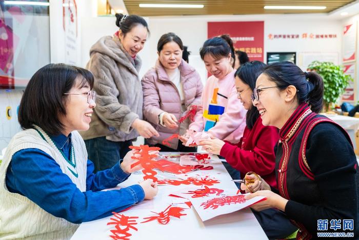 志願者和社區居民在呼和浩特市玉泉區清泉街社區製作春字和龍年剪紙