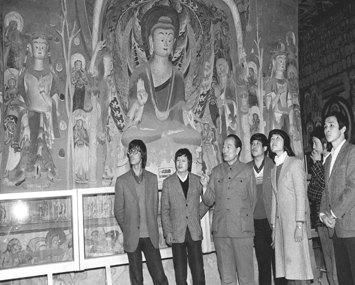  1987年，时任敦煌研究院院长段文杰（左三）向年轻大学生介绍敦煌石窟壁画艺术。 新华社记者 张生贵 摄