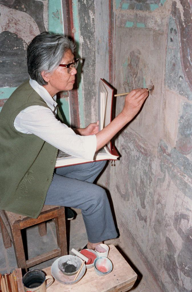 1989年，时任敦煌研究院美术研究所副所长李其琼正在精心描绘复原在原壁上的被盗壁画。新华社记者 李生才 摄