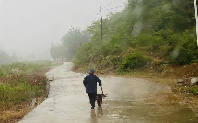 一位老人推着车走过村庄的水泥路，调研的老师拍下了这一幕。受访者供图