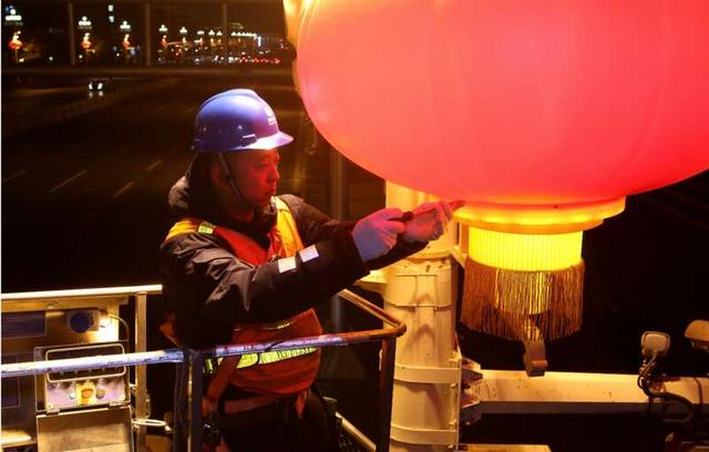 2月1日晚，国网北京市城市照明管理中心工作人员正在调试长安街上悬挂的大红灯笼。张超/摄