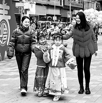     春节前，在江西省九江市浔阳区浪井广场，家长带着孩子置办年货，感受传统热闹的过年氛围。朱兰华摄/光明图片
