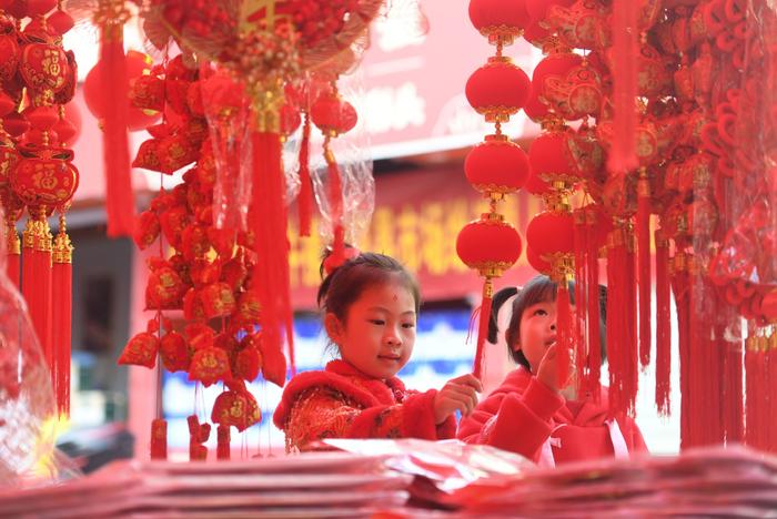 2024年2月1日，在湖南省永州市道县城区年集市场，两名小朋友在挑选新春饰品。通讯员 蒋克青 摄