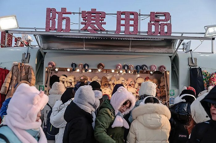 哈尔滨冰雪大世界门口卖防寒用品的临时店铺挤满了人。