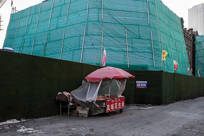 一个花生米摊摆在被绿布包裹的老欧式建筑前。