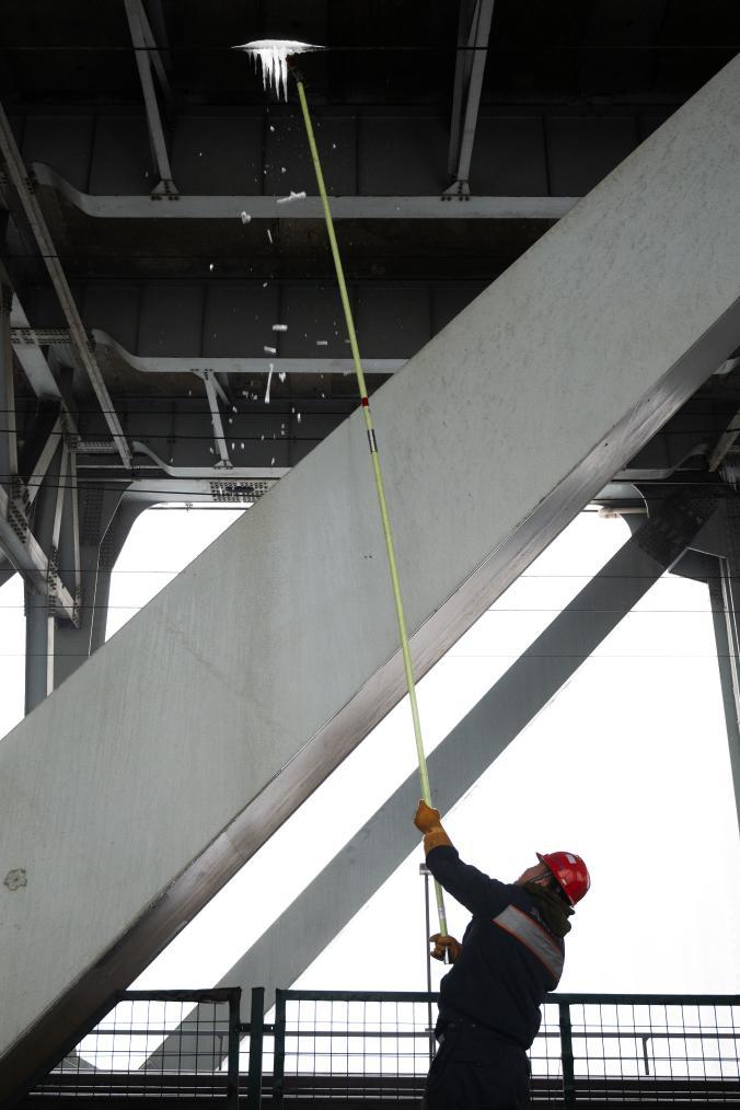   2月4日，在武汉天兴洲长江大桥，武汉供电段工人对铁路接触网设备进行除冰作业。 新华社记者 肖艺九 摄