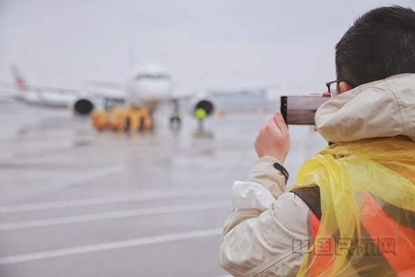 本报记者钱擘在虹桥机场机坪采访C919执飞春运航班（胡夕姮/摄）