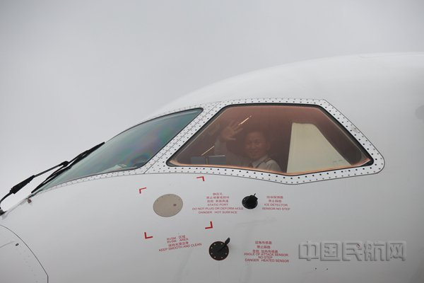 执飞当天航班的机组，在驾驶舱里，向机坪上采访的本报记者挥手执意（胡夕姮/摄）