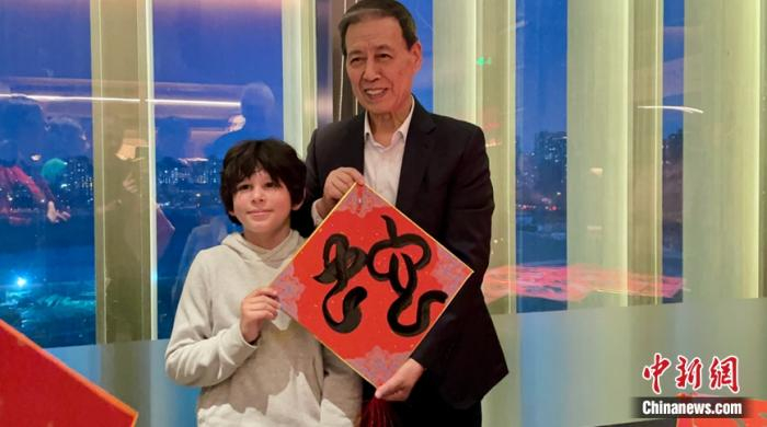 中国书法家修先台先生向法国小男孩赠送书法作品。中新网黄方摄