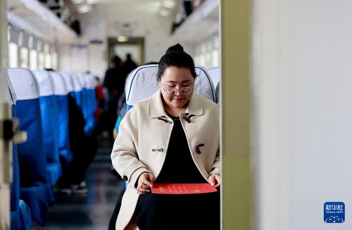 　　苏媛婷手持婚书坐在杜永其值乘的K4081次列车车厢中(2月1日摄)。新华社记者 李嘉南 摄