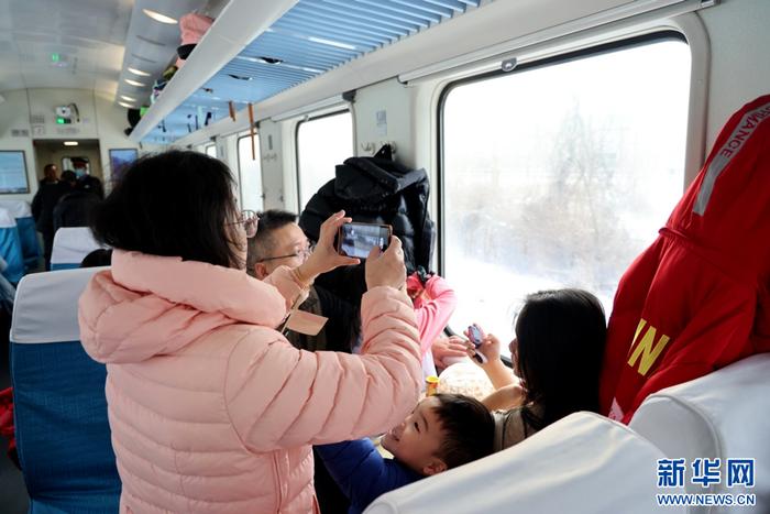 游客在慢火车上用手机拍摄沿途的冬日风景。 新华网发 曲晓曦摄
