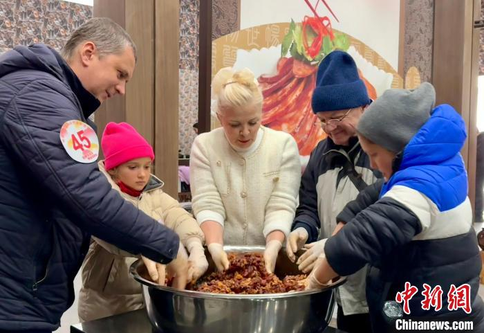多名国际友人搅拌切好的腊肠原料。项菁 摄
