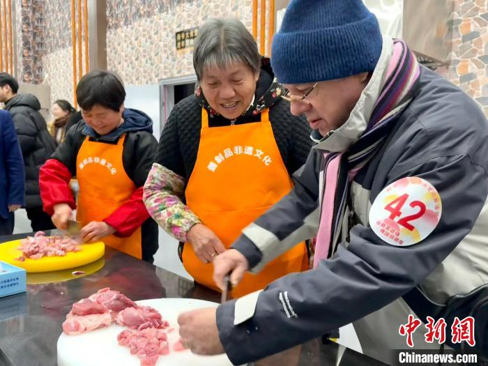 国际友人在本地阿姨的指导下，尝试切腊肠所需的肉。项菁 摄