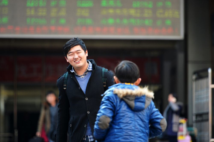 2015年2月18日,在兰州火车站,一名到达旅客见到孩子后露出笑容.