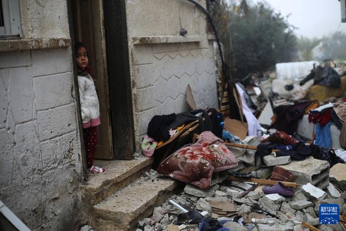   2月9日，在加沙地带南部城市拉法，一名女孩站在以军空袭后的废墟旁。新华社发（哈立德·奥马尔摄）