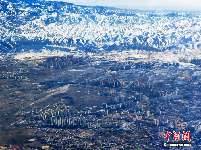 从空中拍摄的天山雪峰下的乌鲁木齐市。王小军 摄