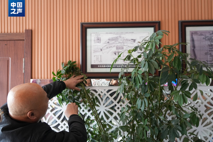 △魏世恒在旅馆前厅的墙面上挂满了中东铁路相关的历史资料，他常为对横道河子铁路发展史感兴趣的客人讲解。（记者韩雪莹 摄）