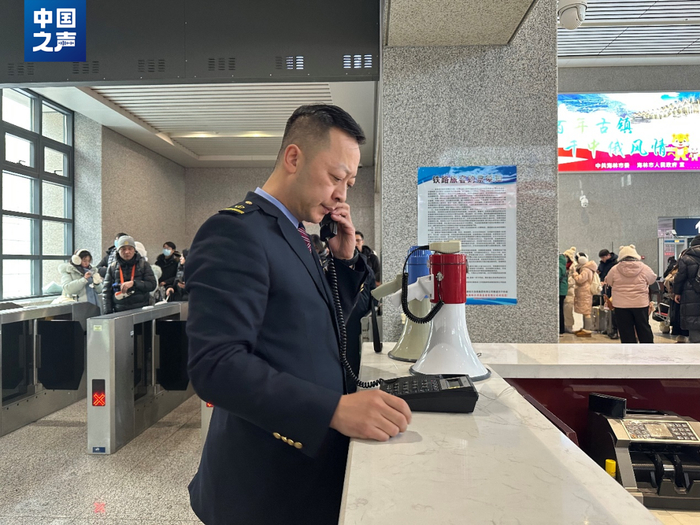 △客流高峰期，横道河子东站站长王冰联系客运中控提前检票（记者韩雪莹 摄）