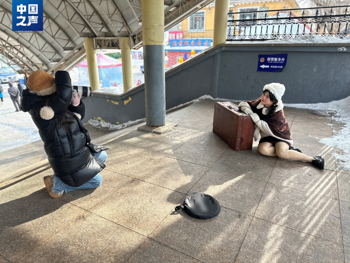 △本地摄影师小王为浙江游客孙姑娘拍摄火车站主题肖像。（记者韩雪莹 摄）