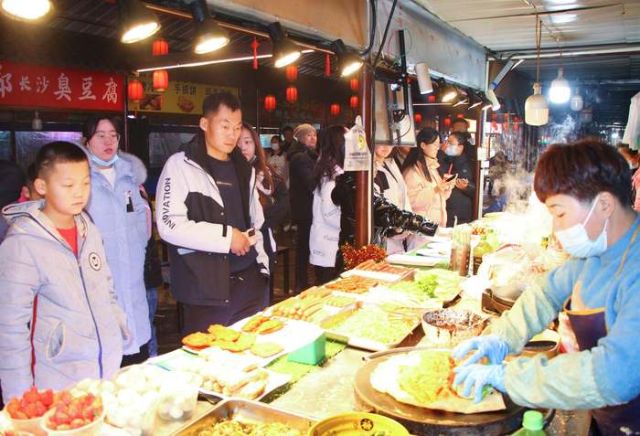 1月8日晚,十三师新星市天街步行街夜市内顾客正在排队等餐.