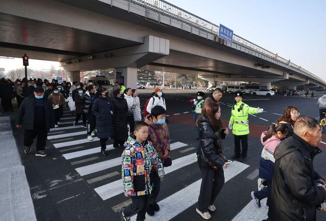 2月13日早上9点半，在北二环雍和宫桥下路口，前往地坛庙会的游客正通过斑马线。  新京报记者 王贵彬 摄